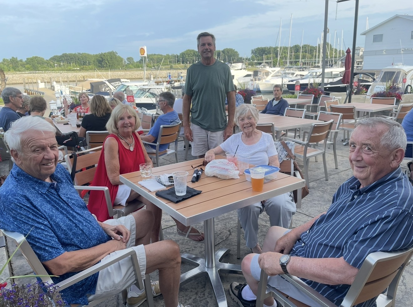 Members gathered around a patio table by the marina on a summer evening